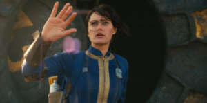 ella-purnell-puts-her-hand-up-while-looking-up-at-the-sky-in-fallout